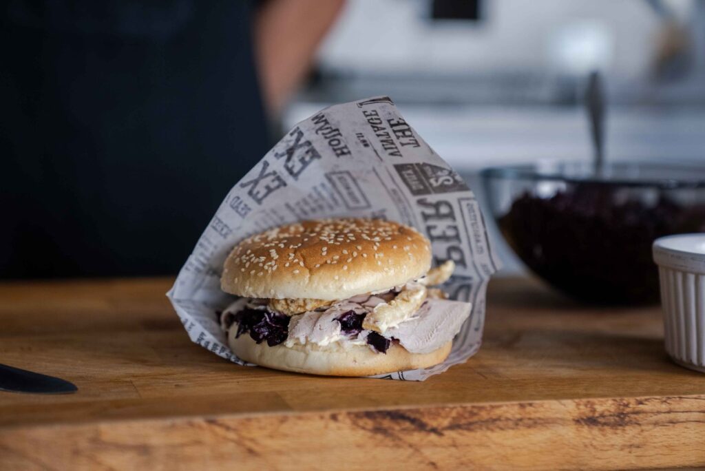 Flæskestegsburger med sprød svær og rødkål på bræt.