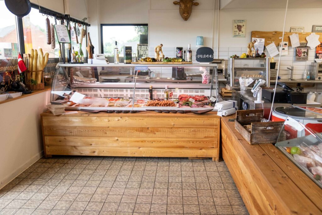 Slagterbutik med køledisk fyldt med friske udskæringer og pølser.